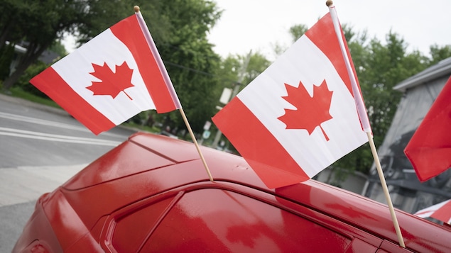 Des drapeaux du Canada sur une voiture.