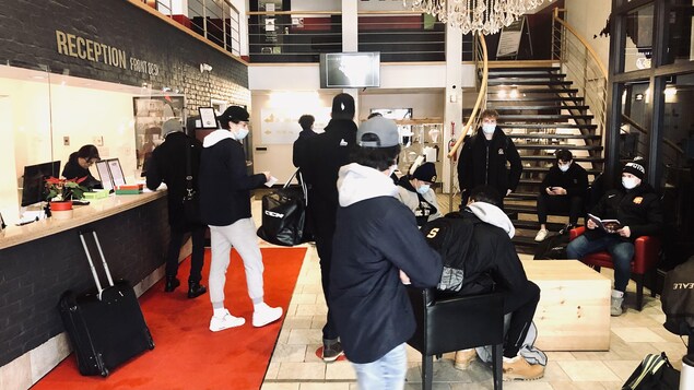 Des joueurs de hockey et leurs valises dans un hall d'hôtel.