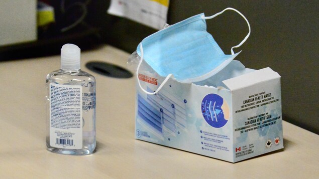 Une bouteille de gel désinfectant à côté d'une boîte de masques.