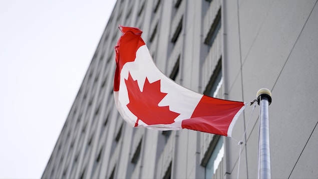 Le drapeau du Canada vogue devant l'édifice.