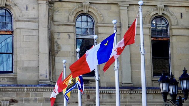 Les drapeaux du Canada, de l'Acadie et du Nouveau-Brunswick devant l'édifice de l'Assemblée législative