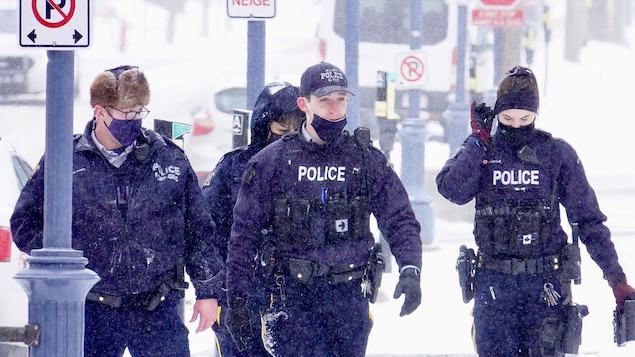 Quatre policiers de la GRC marchent sous la neige.