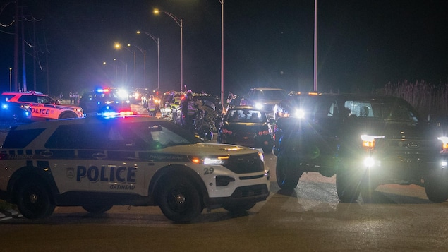 De nombreuses voitures de police bloquent le chemin à des véhicules qui se trouvaient au rassemblement d'une course de rue en pleine nuit.