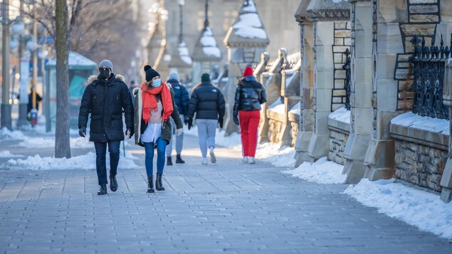 Des piétons qui portent le masque sur un trottoir à Ottawa.