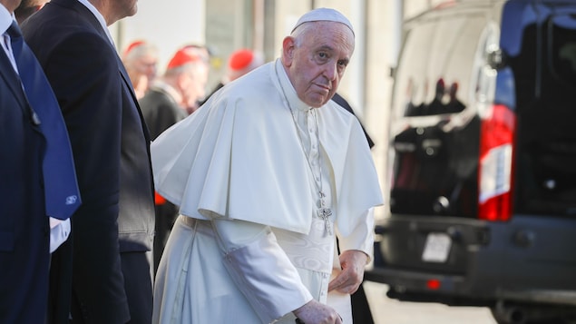 Le pape François est debout et regarde l'objectif de la caméra