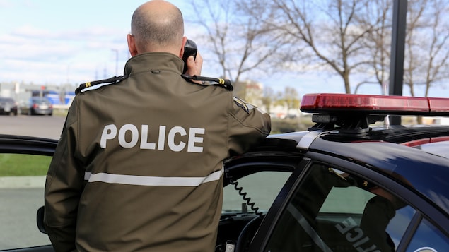 Un policier de dos parle dans un téléphone mobile.