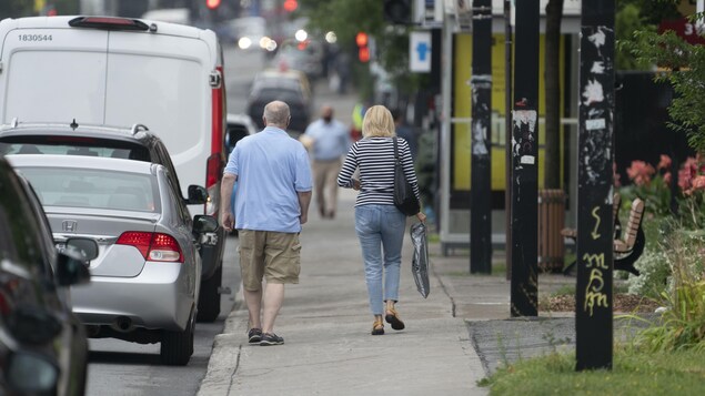 Un homme et une femme, de dos, marchent sur un trottoir.