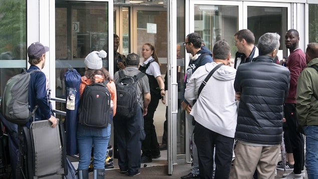 Des gens attendent devant le bureau des passeports à Montréal.