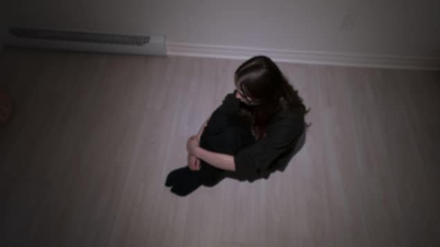 Une jeune fille est assise seule au sol.
