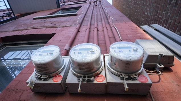 Trois compteurs résidentiels d'Hydro-Québec sur un mur de briques.