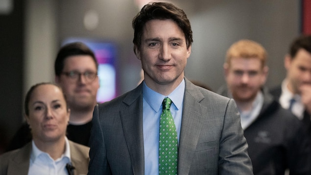 Justin Trudeau marche, entouré de son équipe.