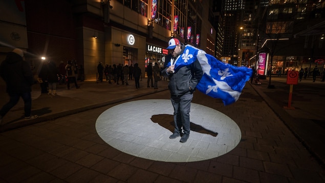 Un homme portant le drapeau du Québec sur son épaule.