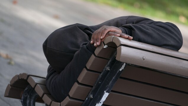 Un itinérant dort sur un banc public.