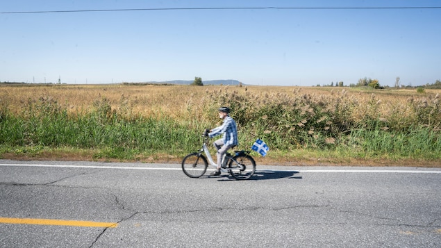 Un homme en vélo devant une terre agricole de Saint-Basile-le-Grand.