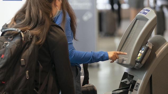 Deux voyageuses à un kiosque d’enregistrement à l’aéroport Montréal-Trudeau.