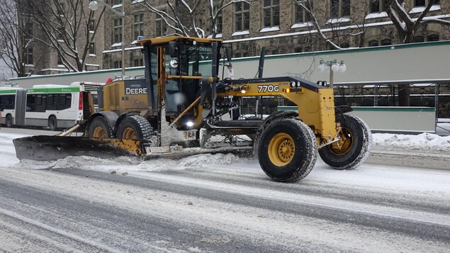 Un immense tracteur jaune sur les rues enneigées du centre-ville d'Ottawa.