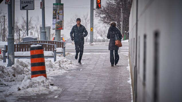 Un homme fait son jogging au centre-ville d'Ottawa sous de légers flocons.
