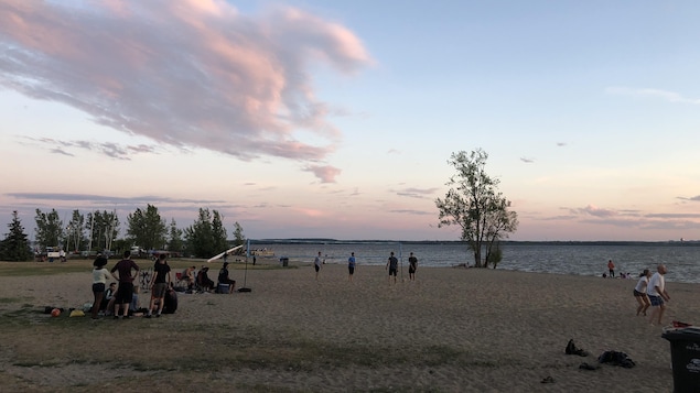 Une plage en fin de journée avec quelques dizaines de visiteurs.