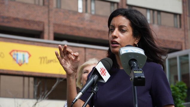 La femme s'adresse aux journalistes, devant des micros.
