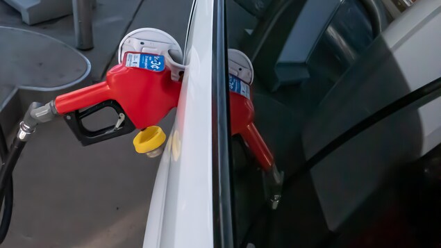 L'embout d'une pompe à essence inséré dans le réservoir d'une voiture.