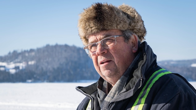 Guy St-Pierre avec son chapeau de fourrure et son manteau de travailleur, sur le lac gelé. 