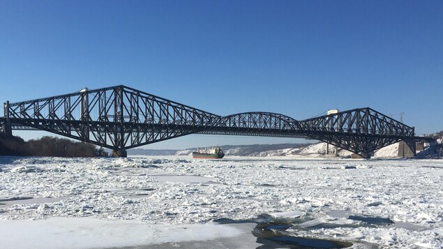 Un navire passe sous les ponts de Québec et Pierre-Laporte en hiver.