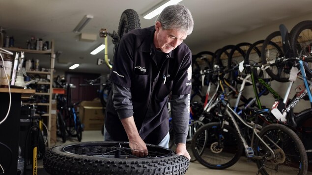 Un homme qui installe un pneu de vélo dans un magasin de vélo. 