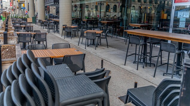 Des chaises sont empilées sur la terrasse vide d'un restaurant.