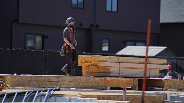 Un travailleur de la construction marche sur un plancher en bois à l'extérieur.