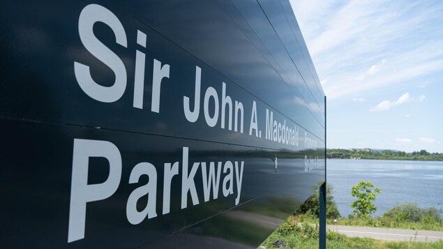 Un panneau indiquant la promenade Sir-John-A.-Macdonald avec la rivière des Outaouais en fond.