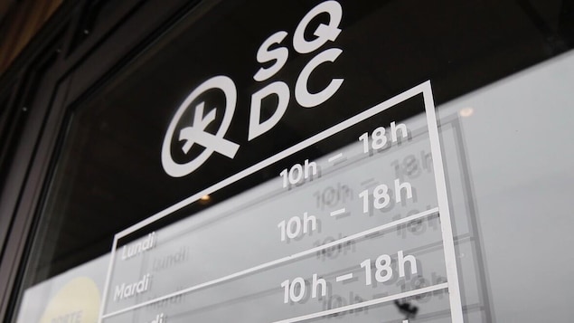 La porte d'une succursale de la SQDC, sur laquelle sont affichées les heures d'ouverture.