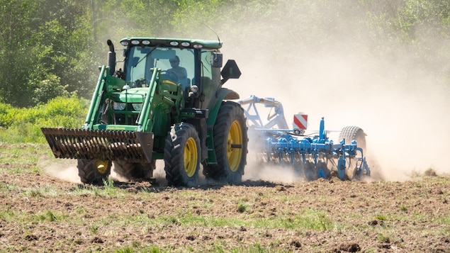 Un cultivateur sur un tracteur dans un champ.