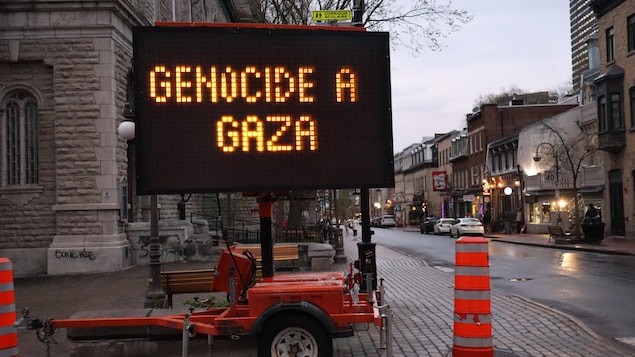Un panneau afficheur sur remorque de la Ville de Québec installé en bordure de la rue Saint-Jean affiche les messages « CANADA COMPLICE » ET « GENOCIDE A GAZA ». 
