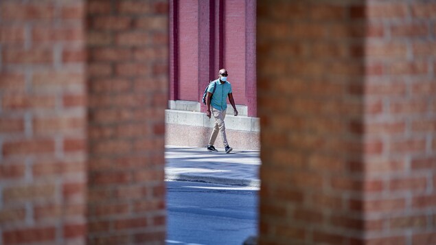 Une personne avec un masque marche dans une rue.