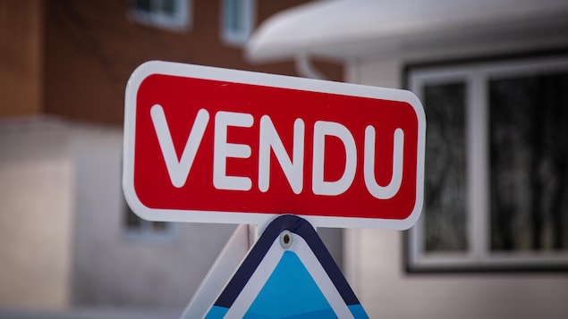 Carton « vendu » installé sur une affiche de courtier immobilier