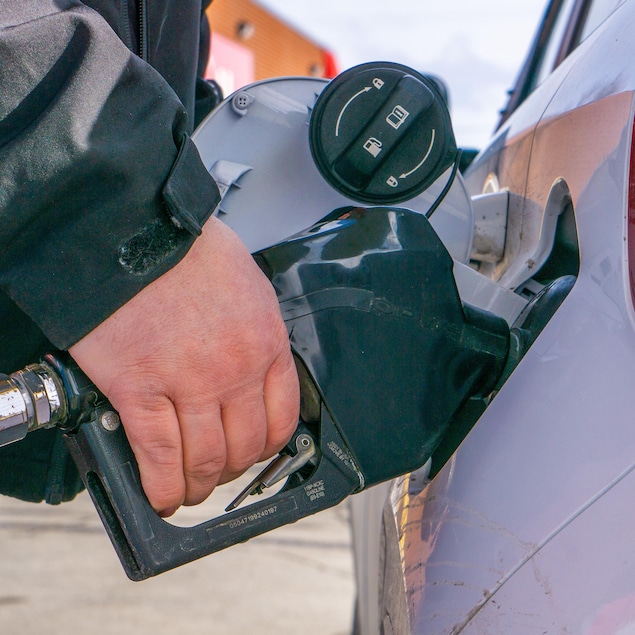 Une main tenant une pompe à essence en train de faire le plein.