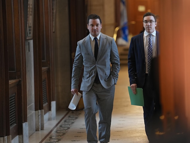 Simon Jolin-Barrette marche dans un corridor de l'Assemblée nationale en compagnie d'un autre homme.