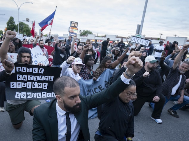 Des manifestants agenouillés lèvent le poing en l'air.