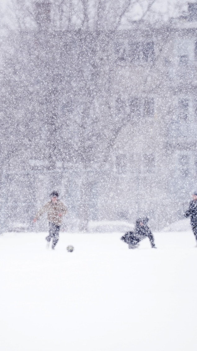 Des enfants jouent au soccer dans la neige.
