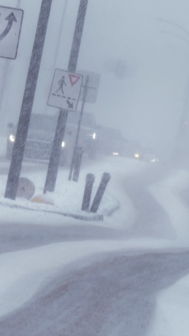 Des voitures circulent sur une route dans des conditions météo difficiles.