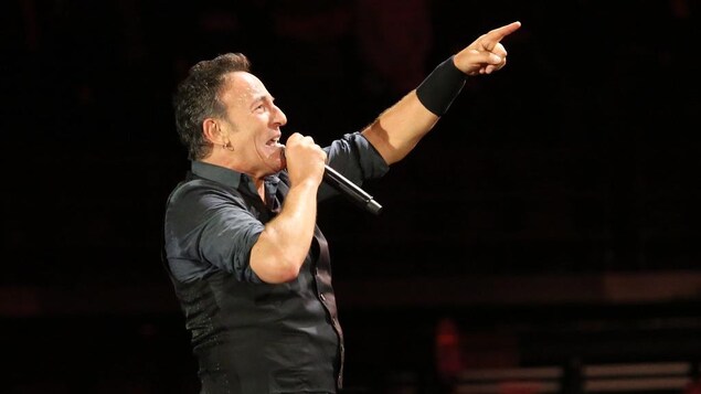 Bruce Springsteen chantant dans un micro sur scène.