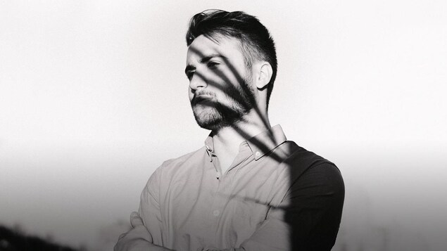 Photo en noir et blanc de Cédrik St-Onge; il semble avoir des ombres de minces palmes d'arbre au visage.