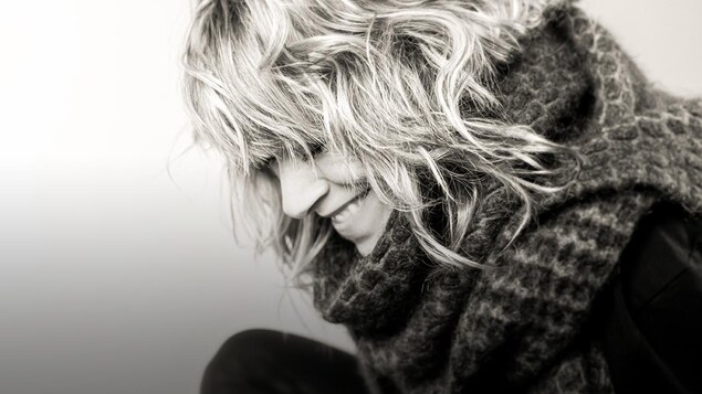 Photo noir et blanc : la chanteuse Luce Dufault, de profil, tout sourire. Elle porte un chandail en lainage au large col. 