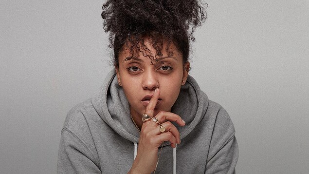 La rappeuse met son index devant sa bouche en signe de silence.