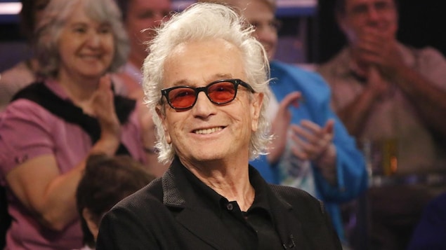 L'artiste sourit sur un plateau devant une foule. 