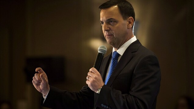 Un homme en complet tient un microphone. Un homme en complet tient un microphone.