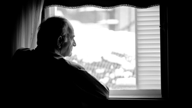 Un homme regarde par la fenêtre.