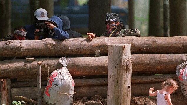 Des Mohawks autour de la barricade érigée lors de la crise d'Oka, en 1990 Des Mohawks autour de la barricade érigée lors de la crise d'Oka, en 1990