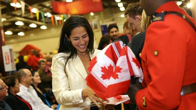 سيدة مهاجرة مسرورة بحصولها على الجنسية الكندية خلال حفل رسمي.