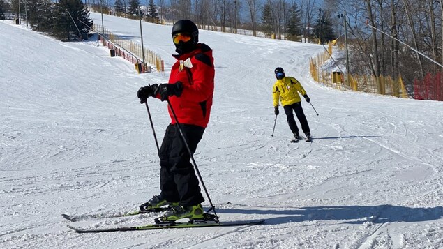 Deux skieurs descendent les pentes. 